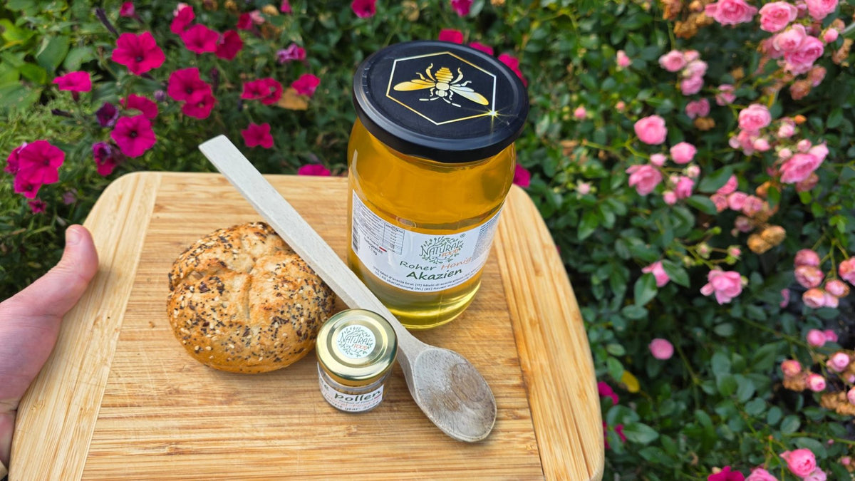 Jar of acacia honey with a bread roll and wooden spoon
